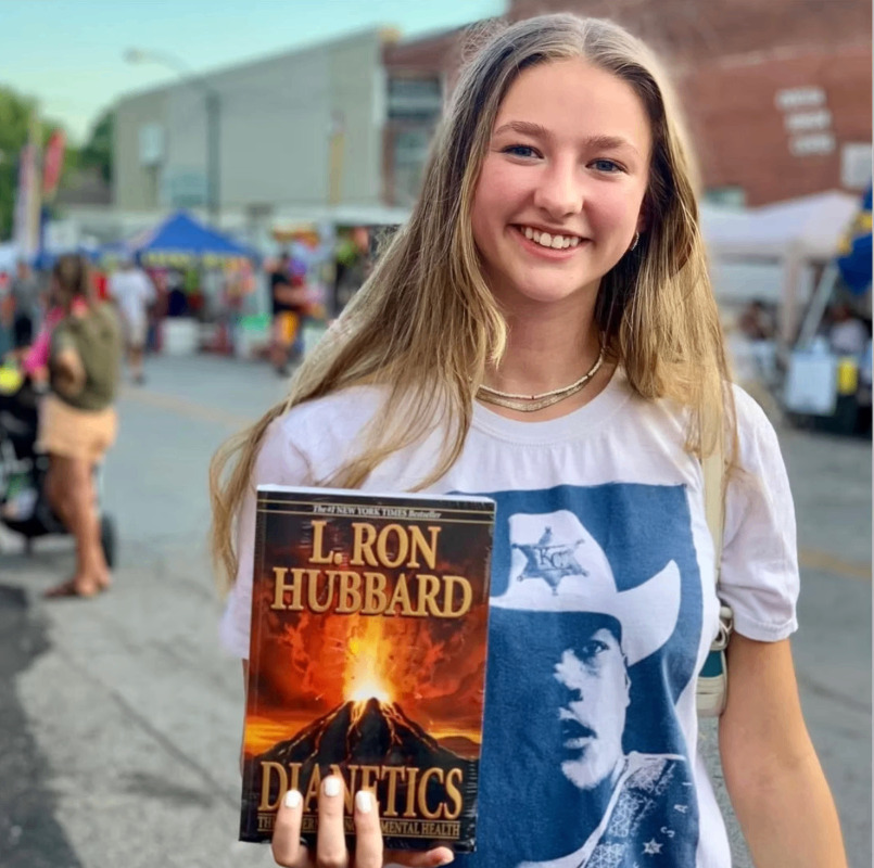 Lectora de Dianética sonriendo con el libro